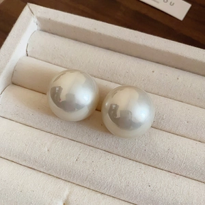 Vue rapprochée de grandes boucles d'oreilles perles blanches rondes au lustre miroir élégant
