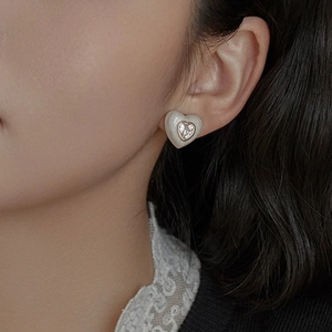Close-up of elegant heart earrings with white inlay and diamond on a model