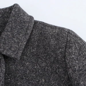 Detail shot of grey wool blend coat showing tweed fabric texture on lapel and shoulder