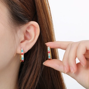 Vue détaillée de boucles d'oreilles dorées en U avec pierres arc-en-ciel rectangulaires