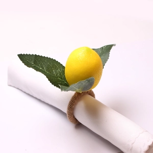 Handmade lemon napkin ring with green leaves and jute rope on white fabric