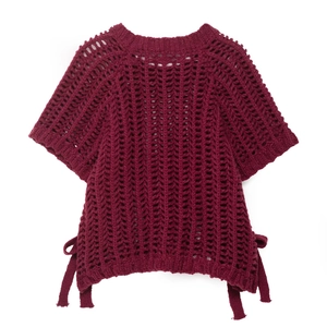 Detail of burgundy openwork crochet knit top featuring thick texture and side lace-up ties