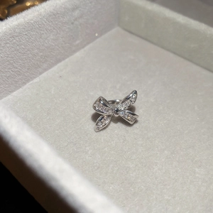Close-up of silver bow ear cuff with inlaid clear cubic zirconia on jewelry box