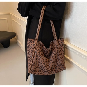 Detail of a large leopard print fabric tote bag styled with a long black winter coat