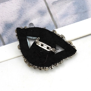 Detail view of the silver pin fastening on the back of the crystal evil eye brooch