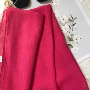 Detail of rose red lightweight silk scarf with sunglasses and pearls on white fur