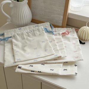 Detail of drawstring storage bags with bow prints and soft fabric textures for travel