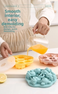Filling yellow cartoon silicone cat paw mold with orange juice in a bright kitchen