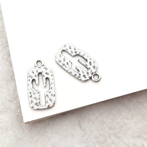 Detailed close-up of retro silver cactus charms for DIY jewelry making with hammered texture