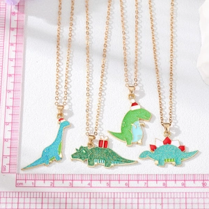 Detail of four colorful glitter enamel dinosaur necklaces with gold chains and a ruler