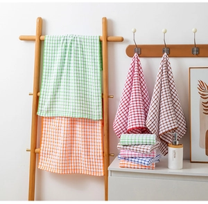 Detail of colorful plaid cotton tea towels hanging on a wooden ladder and wall hooks