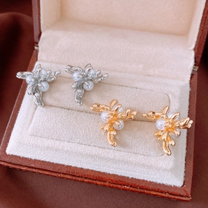 Detailed macro view of gold and silver coral branch earrings with white pearls in a jewelry box