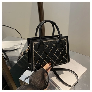 Détail du sac bandoulière noir avec broderie de cœurs dorés et texture en simili cuir