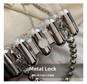Detail of silver acrylic evening bag showing metallic ball handle and round clasp