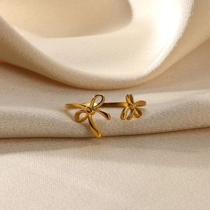 Detail view of gold floral and bow-knot ring on beige silk fabric with natural lighting