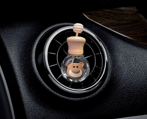 Detail of cute bear cartoon perfume bottle mounted on car air vent outlet