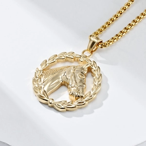 Detailed macro of a gold hollow horse head pendant with a box chain on a white background