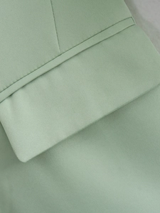 Detail of sage green blazer fabric showing fine texture and precise stitching lines