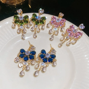 Detailed view of floral drop earrings with colorful zircon tassels on a ceramic plate