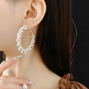 Macro shot of large golden spiral earrings with pearl inlay worn by a female model