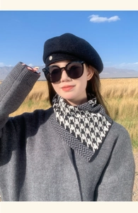 Detail view of a classic black and white houndstooth scarf worn in a scenic outdoor setting