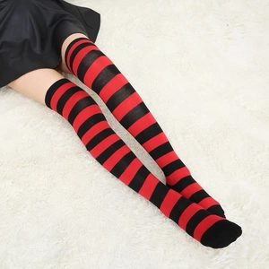 Zebra striped over-the-knee socks in red and black knit, worn on a plush white rug