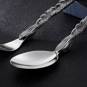 Macro detail of punk dragon handle stainless steel spoons with intricate scale texture