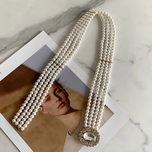 Detail of multi-strand pearl belt with a round rhinestone buckle on marble background