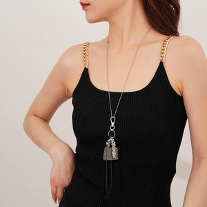 Détail d'un long collier avec pendentif sac en perles et franges grises sur mannequin