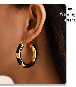 Side view of model wearing large gold-plated hoop earrings with black leopard enamel finish