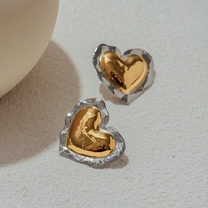 Macro detail of heart-shaped earrings with dual-tone gold and silver hammered texture