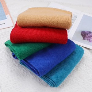 Stack of colorful knitted scarves in camel, red, green, royal blue, and peacock blue