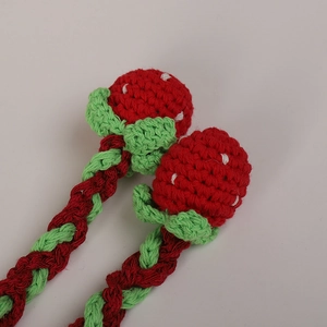 Handmade crochet strawberry hat tassels with vibrant red yarn and green leaf detail