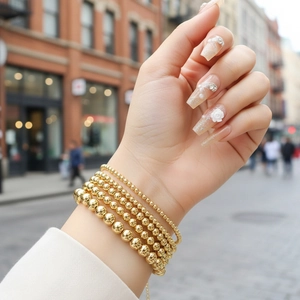 Close-up of four-piece set 18K gold beaded elastic bracelets styled on model wrist
