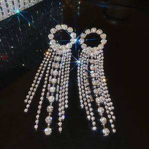Detailed view of silver hoop earrings with shimmering crystal rhinestone tassels on black base