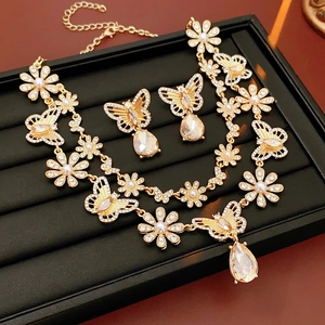 Détail du collier et des boucles d'oreilles vintage dorés avec papillon et cristal
