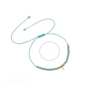 Macro detail of mint green crystal woven bracelet with transparent heart pendant