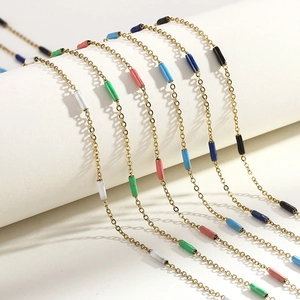Detailed view of 1.5mm titanium gold chains with colorful enamel bead accents