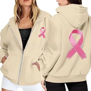 Detail view showing front and back pink ribbon prints on beige zip-up charity hoodie
