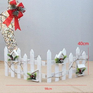 Détail d'une clôture de Noël en bois blanc avec mini cabane, pommes de pin et baies