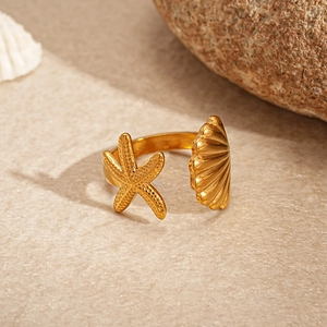 Detailed view of gold starfish and seashell charms on an adjustable open bangle