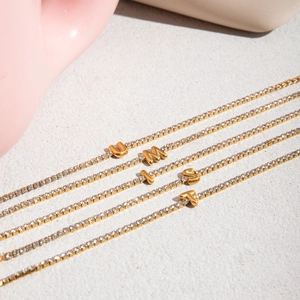 Detailed macro view of five gold tennis bracelets with U, M, L, S, T rhinestone pendants