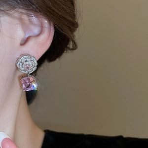 Close-up of camellia earrings with pink square zircon stones on a model