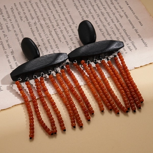 Bohemian geometric wooden earrings with red beaded tassels on a vintage book background