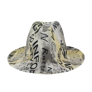 Detail of grey wool fedora featuring black graffiti print and yellow edge stitching