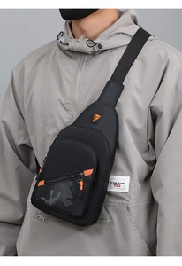 Detail of black crossbody chest bag featuring orange zippers and camo pattern on model