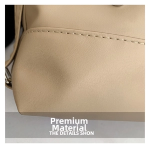 Close-up of beige faux leather texture with precise stitching on a minimalist shoulder bag