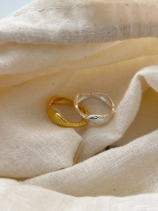 Detail of wavy S925 sterling silver and gold plated rings on cream fabric bag