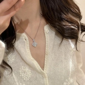 Close-up of elegant silver four-leaf clover pendant necklace with pave-set zircons