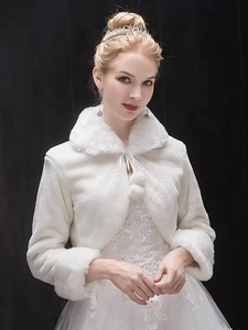 Detailed view of white bridal faux fur bridal shawl with plush pompoms and long sleeves for winter